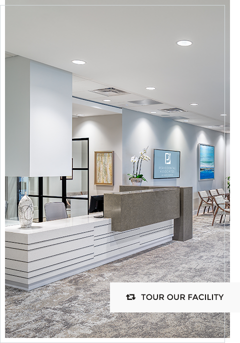 Modern dental office reception area with stone veneer desk, contemporary lighting, and professional design with TOUR OUR FACILITY text
