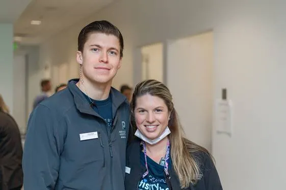 Young male dental staff member and female colleague posing together in modern dental office corridor