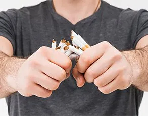 Person's hands breaking cigarettes in half, symbolizing smoking cessation and quitting tobacco
