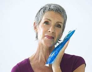 A woman holding an icepack to her jaw